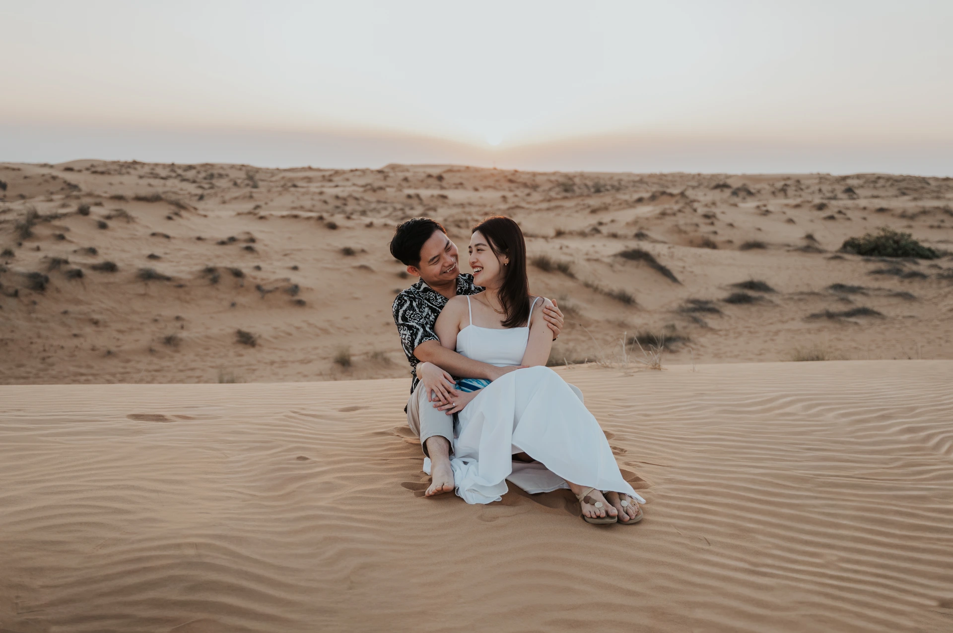 Couple assis dans les dunes lors d’une séance photo à Dubai.